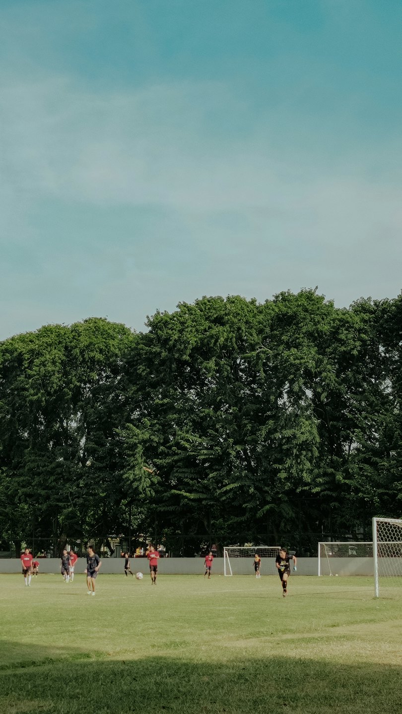 Eine Gruppe von Menschen, die auf einem Rasenplatz Fußball spielen.