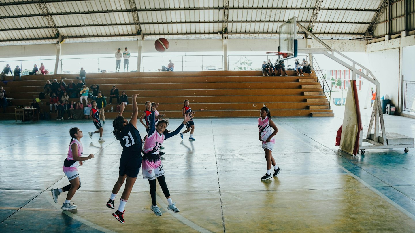 Jugendliche Basketballspieler im Wettkampf während eines Spiels in einer Sporthalle.
